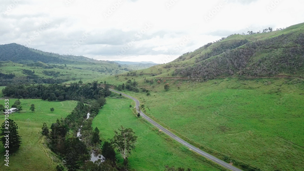 Aerial Drone View Above A Winding Road Through Lush Green Mountain Countryside On An Overcast Day 