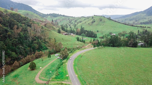 Aerial Drone View Above A Winding Road Through Lush Green Mountain Countryside On An Overcast Day 