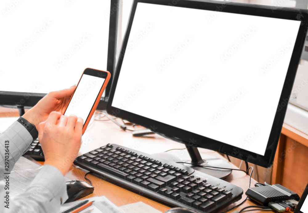 Woman in the office in front of monitors. Closeup of a hand with a phone. Woman in the office in front of monitors. Closeup of a hand with a phone.