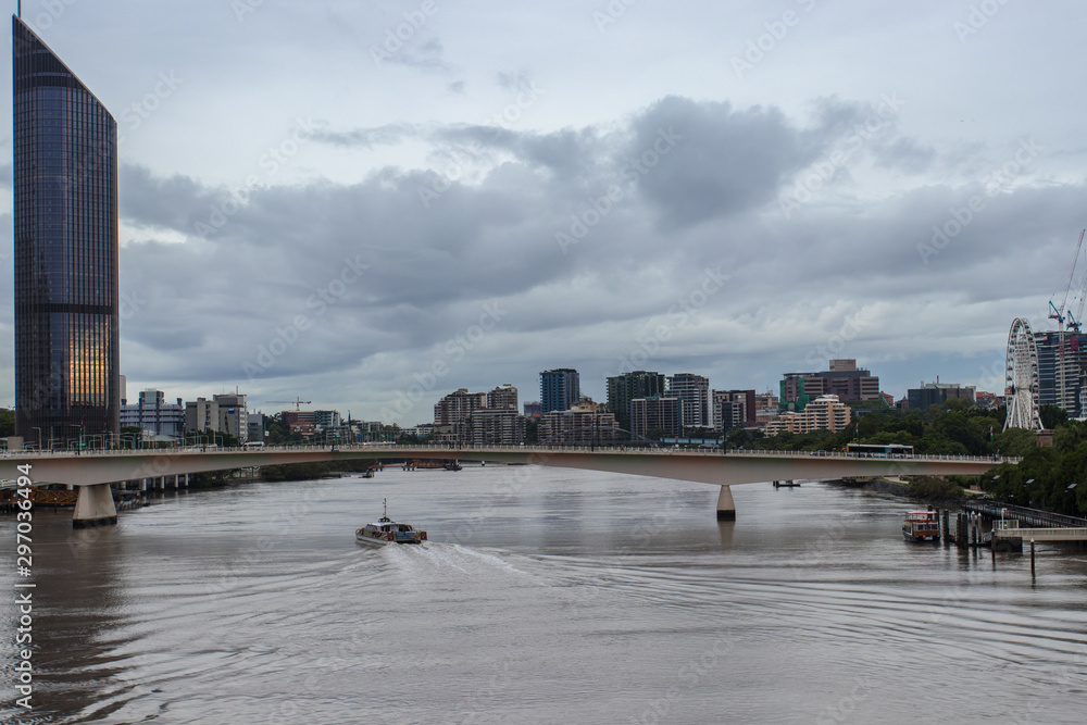 Brisbane City Skyline With High Rises Bridge And Ferry Moving Down The River On An Overcast Day