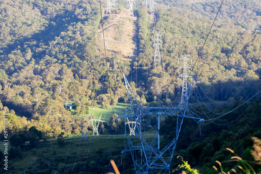 Electrical Power Lines Above Lush Green Mountain Ranges On A Sunny Day In Rural Australia