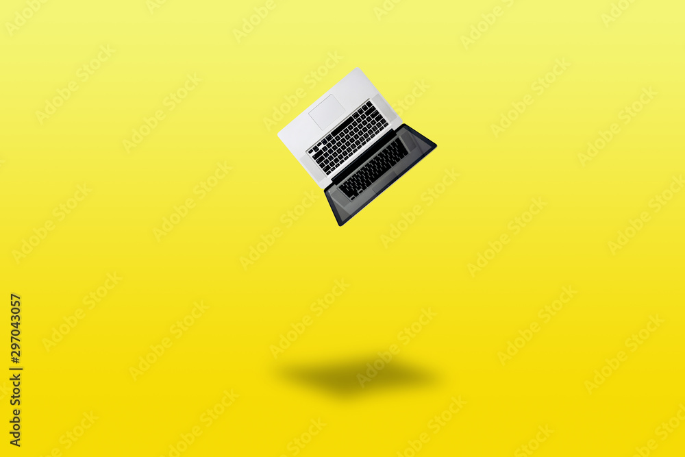 The laptop floats on yellow background The laptop floats on yellow background