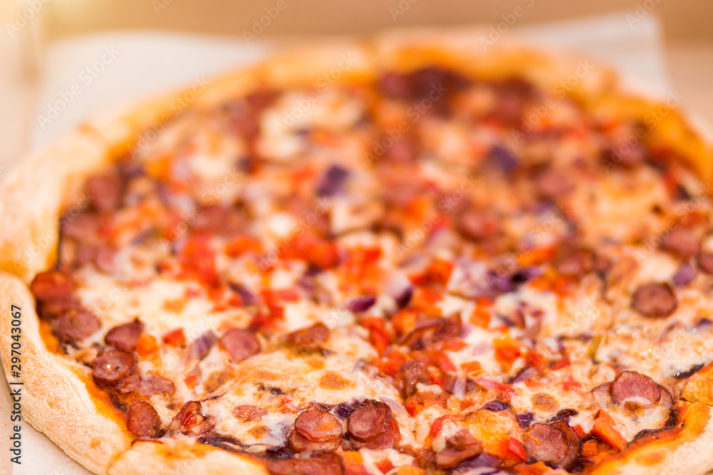 Close-up delicious fresh pizza with sausages, peppers and tomatoes on the table in a box Close-up delicious fresh pizza with sausages, peppers and tomatoes on the table in a box