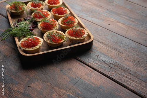 Red caviar in tartalets on a wooden table