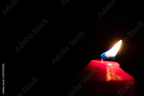 Brennende rote Kerze als Weihnachtskerze oder Weihnachtsdekoration erleuchtet die Dunkelheit und schwarze Nacht in der Adventszeit photo