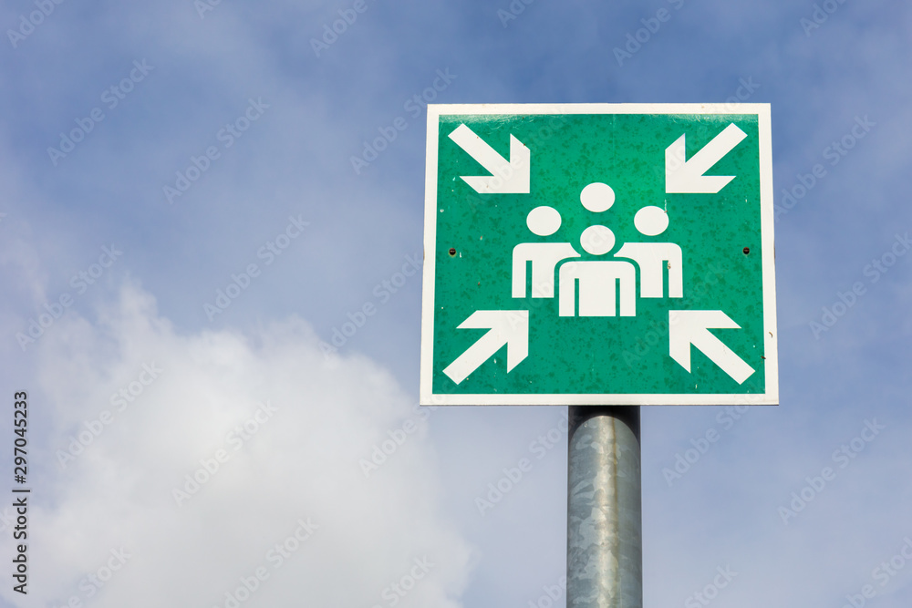 A green sign in front of the airport building shows a meeting place for people, where they can find each other. In the background blue sky and beautiful clouds. A green sign in front of the airport building shows a meeting place for people, where they can find each other. In the background blue sky and beautiful clouds.