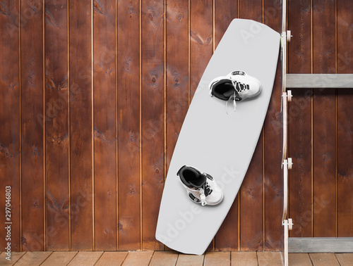 White wakeboard and boots at wooden wall background