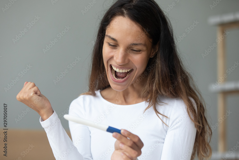 Overjoyed excited young mixed race lady holding pregnancy test. Overjoyed excited young mixed race lady holding pregnancy test.