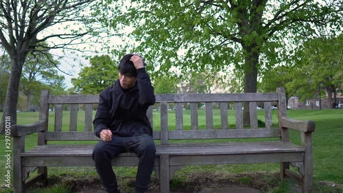 Nervous Young Asian Man Waiting For Date in Park photo