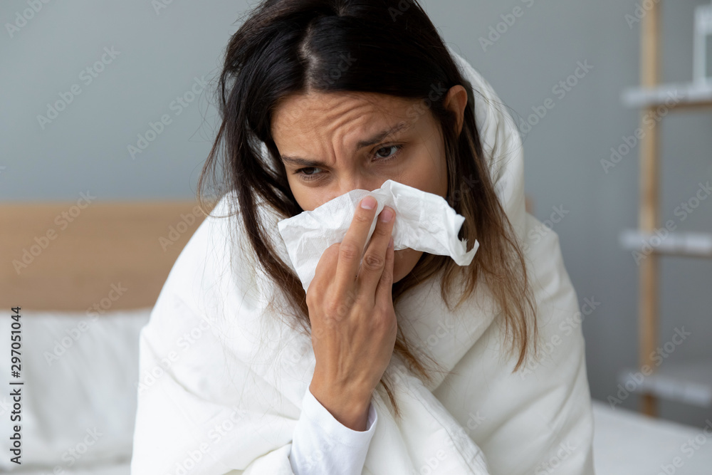 Unhealthy millennial mixed race girl wiping runny nose. Unhealthy millennial mixed race girl wiping runny nose.