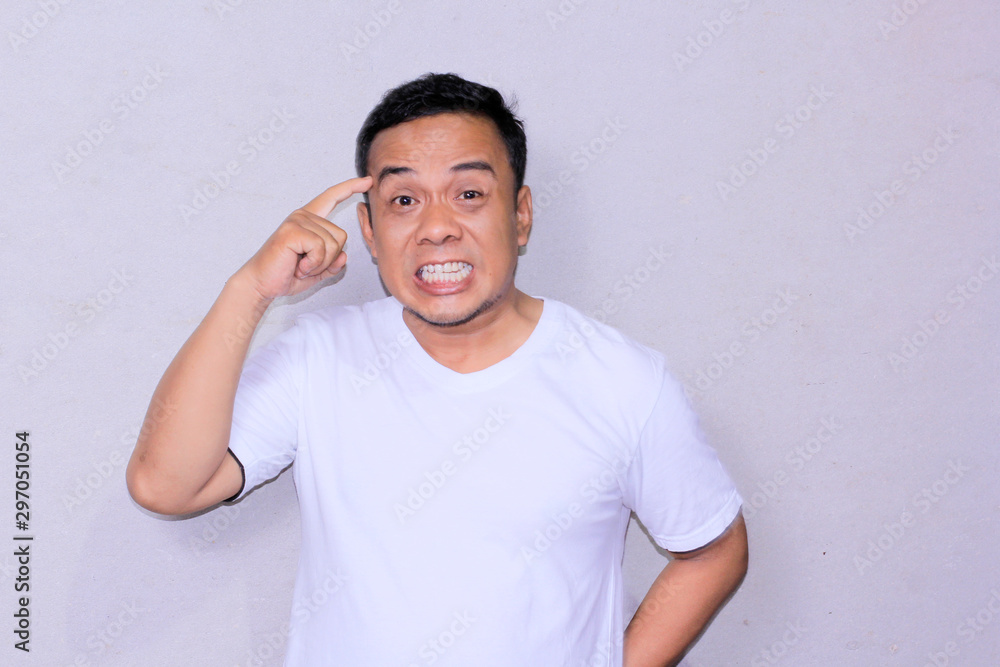 angry asian young man expression while put fown his finger beside his head and say think of that. angry asian young man expression while put fown his finger beside his head and say think of that.