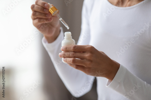 Close up young woman holding bottle with pipette. photo