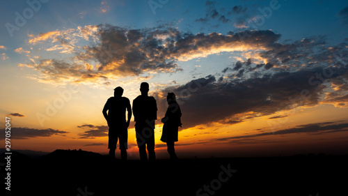 Silhouette of friends standing and watching sunset