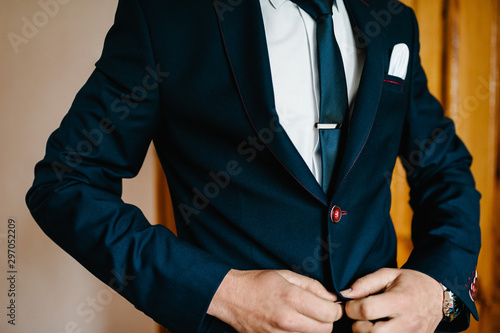 Close-up men's hands fastens the buttons. The groom in a suit, shirt, tie. stylish classic menswear. A part businessman prepares in the morning for a business day or a wedding.