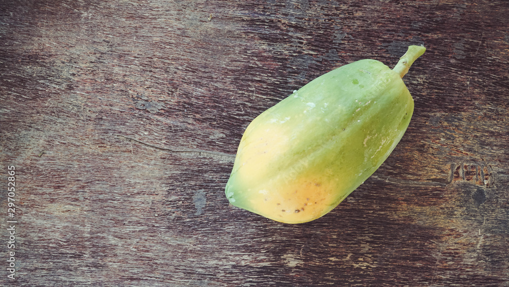 Fototapeta premium one young papaya on an old wooden table
