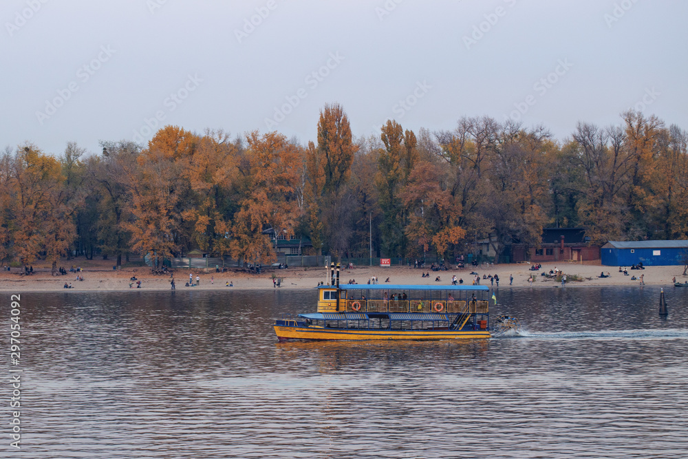 Pleasure boat floating on the river, autumn landscape