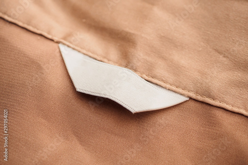 blank white clothing label on brown fabric texture background