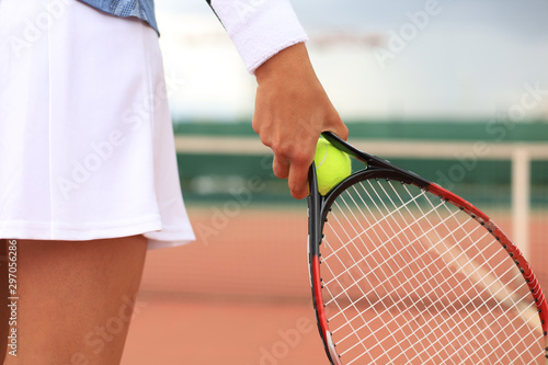 Close up of woman is holding tennis racket on hard tennis court. Tennis ball in player hand. © ty