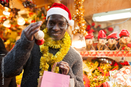 Smiling man in Santa hat selecting festive Christmas decoration