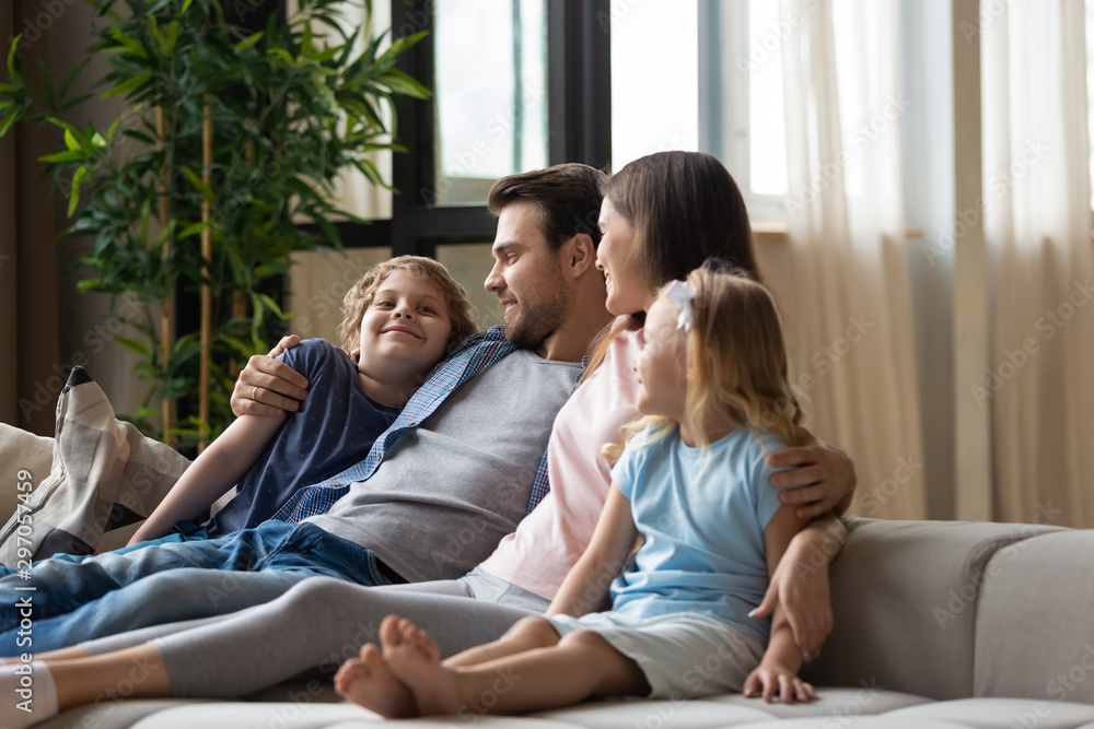 Happy family, mother, father and children hugging, relaxing on couch Happy family, mother, father and children hugging, relaxing on couch