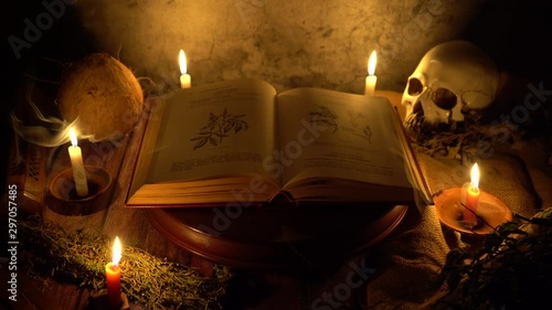 Front view of an old herbal medicine book on a wooden platform with candles and a skull behind