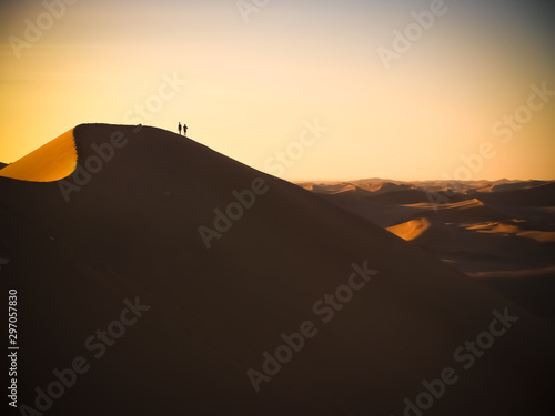 A silhuette of two person walking on a dune in Namib desert