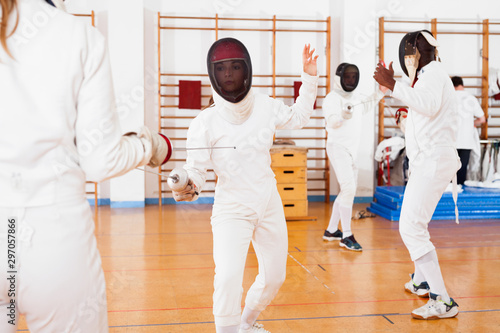 Two female fencers exercising movements in duel at fencing room