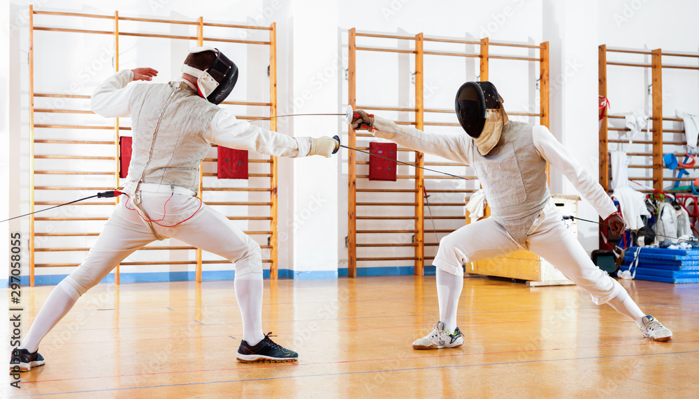 Portrait of athletes at fencing workout, practicing attack movements in duel