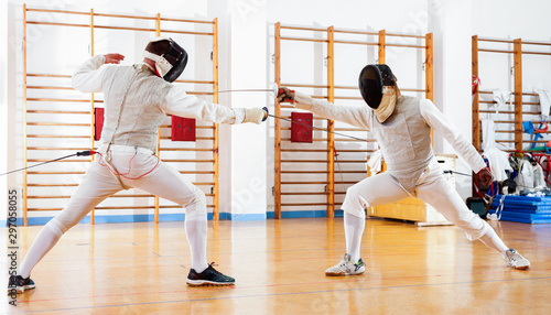 Portrait of athletes at fencing workout, practicing attack movements in duel