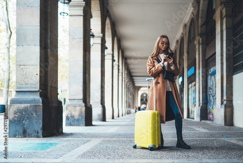 Obraz na plátně Tourist with suitcase holding smart mobile phone