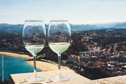 Two drink glass white wine standing on background blue sea top view city coast yacht from observation deck  romantic toast with alcohol panoramic cityscape downtown  spain san sebastian
