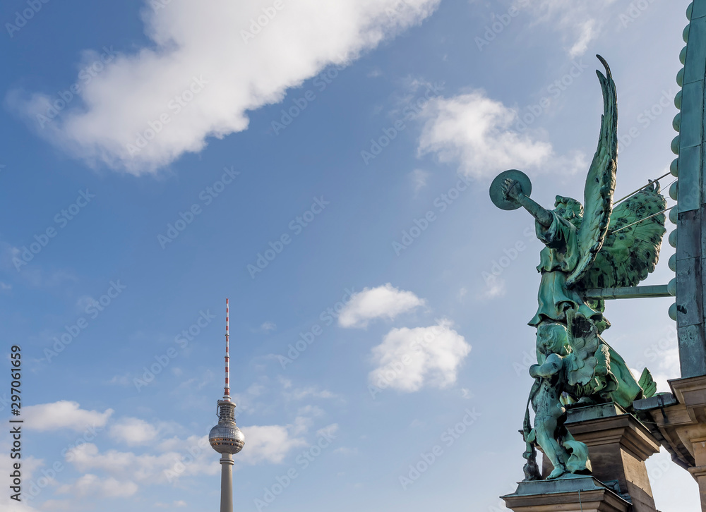 The angel of the dome of the Cathedral of Berlin, Germany and the Television Tower against a beautiful blue sky with some clouds