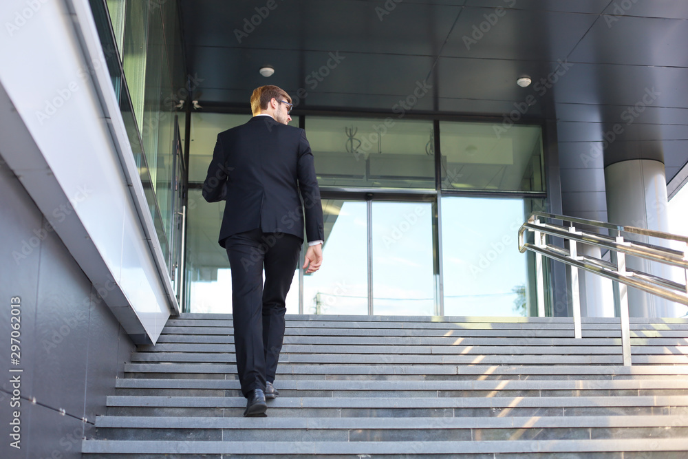 Stylish successful businessman goes up the stairs of the office building. Stylish successful businessman goes up the stairs of the office building.