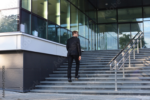 Stylish successful businessman goes up the stairs of the office building. © ty