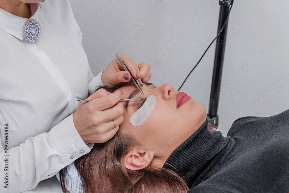 Naklejka premium Eyelash Extension Procedure. Woman Eye with Long Blue Eyelashes. Close up, selective focus.Eyelash removal procedure close up. Beautiful Woman with long lashes in a beauty salon. Eyelash extension.