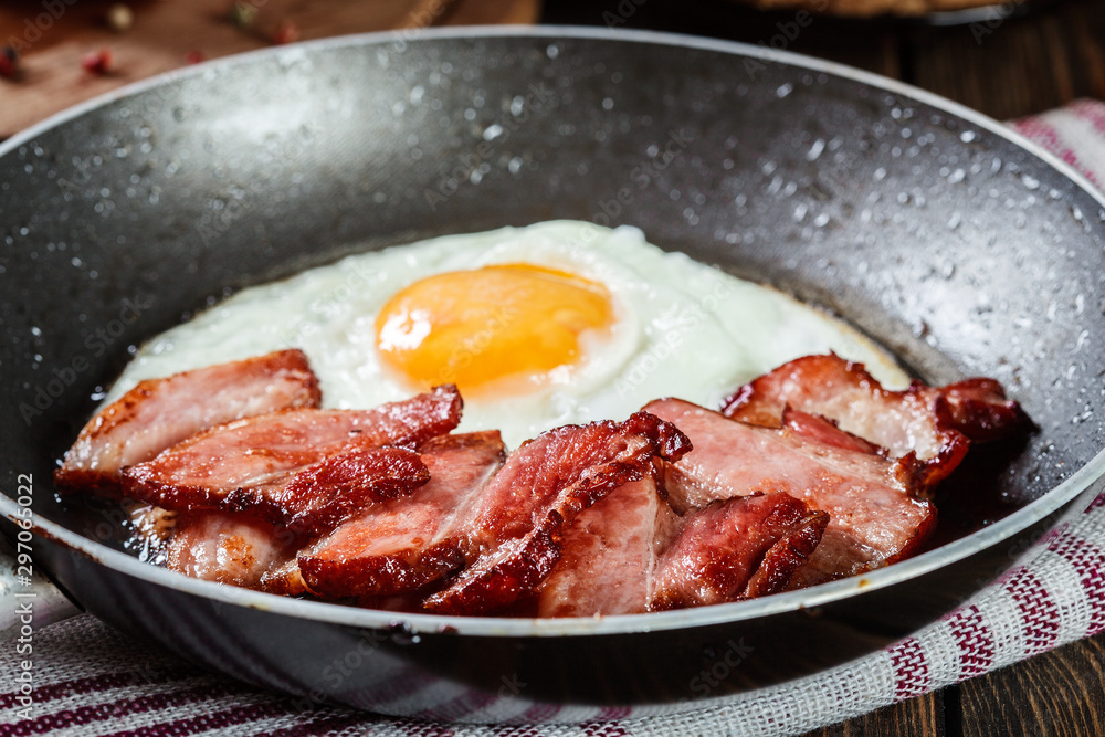 Slices of smoked bacon and fried egg in frying pan Slices of smoked bacon and fried egg in frying pan