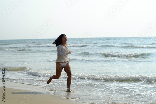 Beautiful young woman in white sportswear running on beach