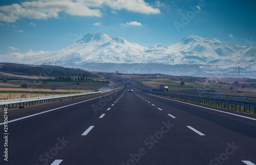 Straight leading highway and snowy mountains in background