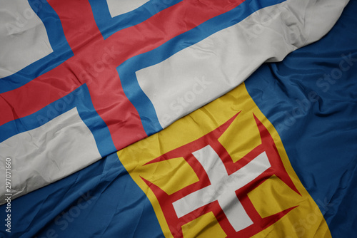 waving colorful flag of madeira and national flag of faroe islands.