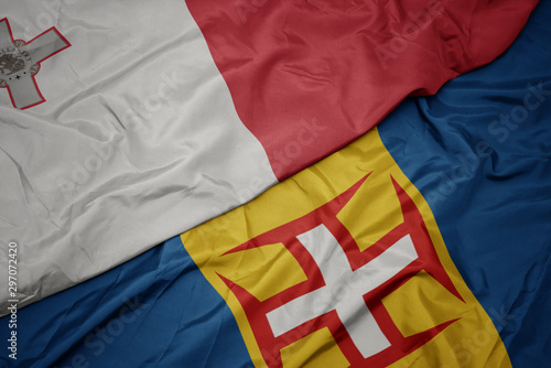 waving colorful flag of madeira and national flag of malta.