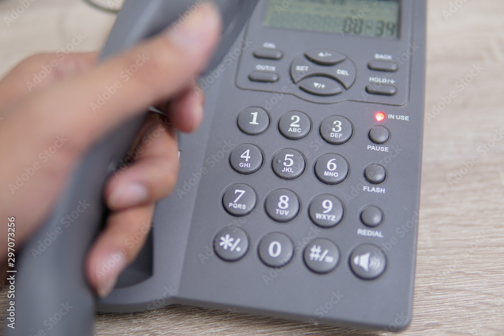 Male hand holding telephone and dailing a phone number. Male hand holding telephone and dailing a phone number.