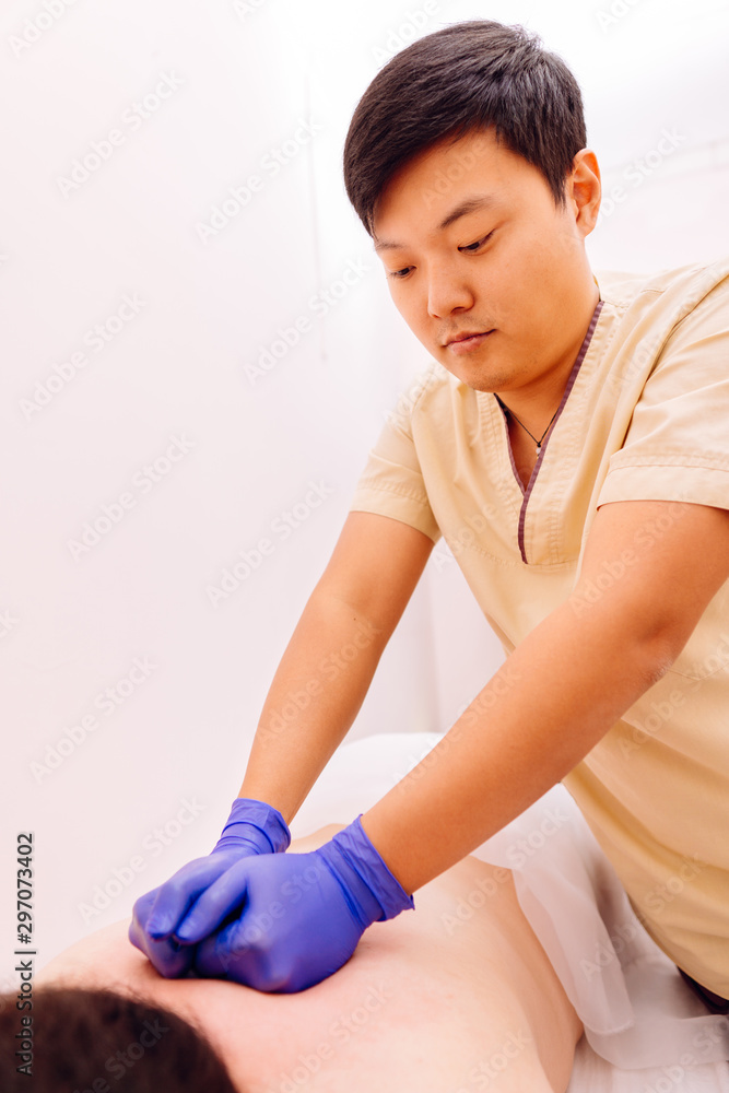 Therapist performing massage on young woman. Chinese traditional massage - Gua Sha. Traditional oriental therapy and beauty treatments. Therapist performing massage on young woman. Chinese traditional massage - Gua Sha. Traditional oriental therapy and beauty treatments.