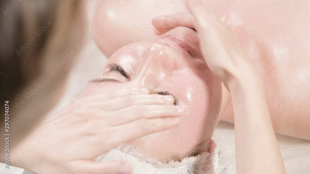 Close-up Spa facial Massage. Girl professional massage therapist does a relaxing facial massage to an attractive client of a spa salon Close-up Spa facial Massage. Girl professional massage therapist does a relaxing facial massage to an attractive client of a spa salon