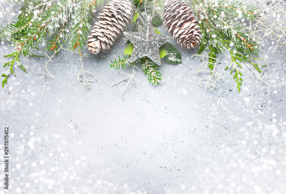 Naklejka Christmas or winter background with a border of green and frosted evergreen branches and pine cones on a grey vintage board. Flat lay
