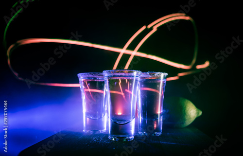 Club drink concept. Tasty alcohol drink cocktail tequila with lime and salt on vibrant dark background or glasses with tequila at a bar