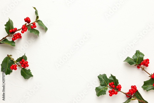 Christmas background with branches of holly with red berries on white. Winter concept. Flat lay, copy space. photo