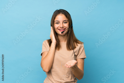Young brunette girl over isolated blue background working with headset