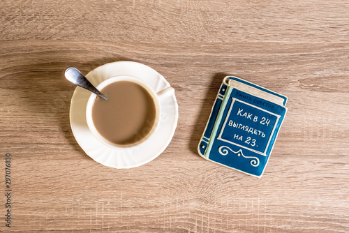 cup of morning coffee latte on a table with cookies in the form of a small book