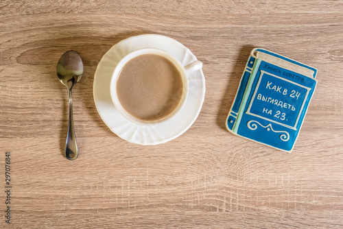cup of morning coffee latte on a table with cookies in the form of a small book