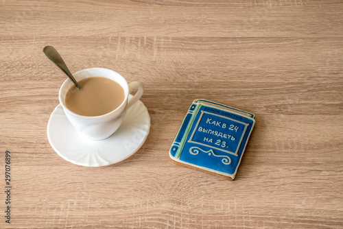 cup of morning coffee latte on a table with cookies in the form of a small book